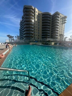 A swimming pool with clear water, surrounded by a high-rise building with multiple balconies.