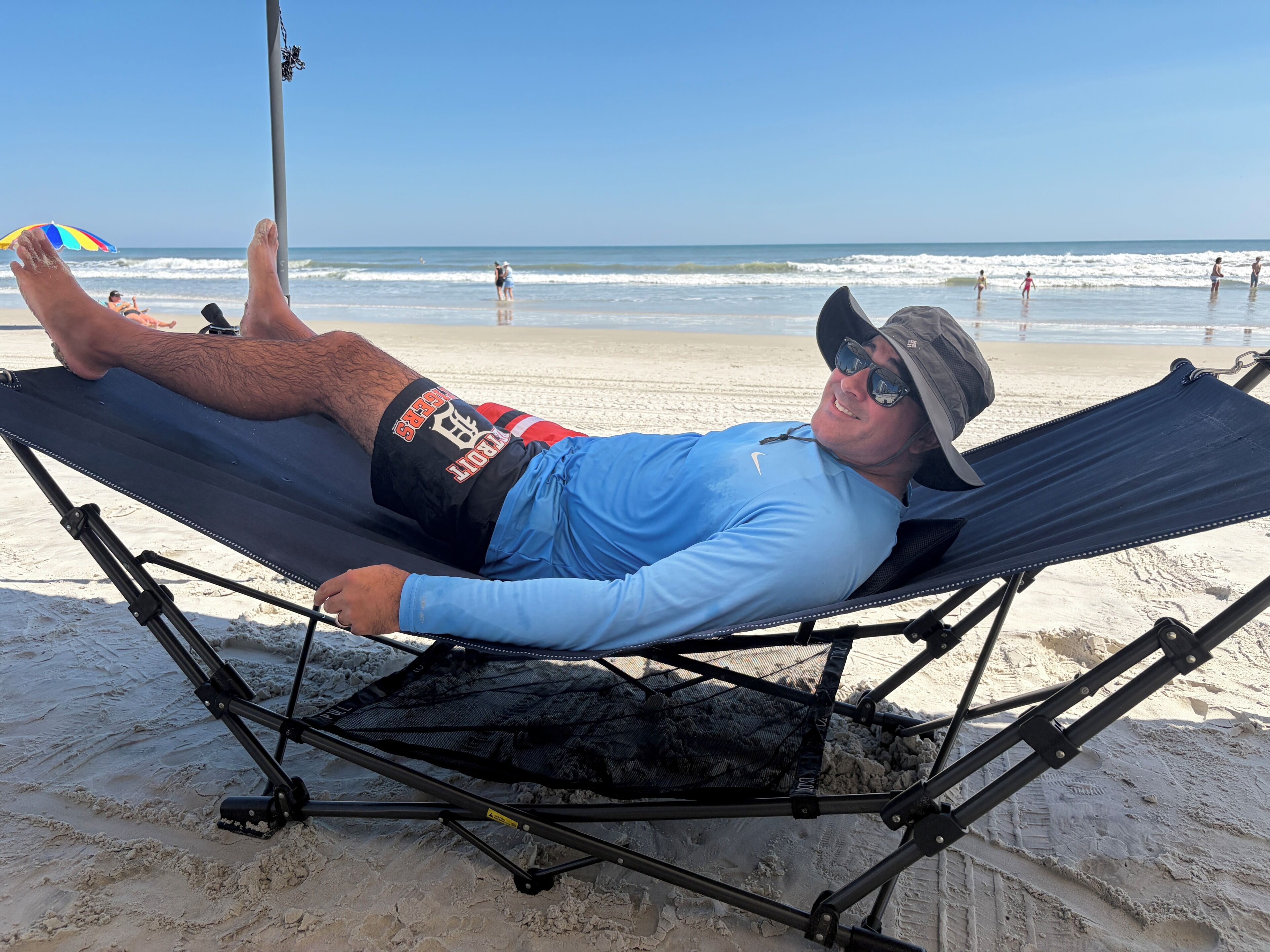 Iemand ligt op een strandstoel, met een strandparasol in de buurt.