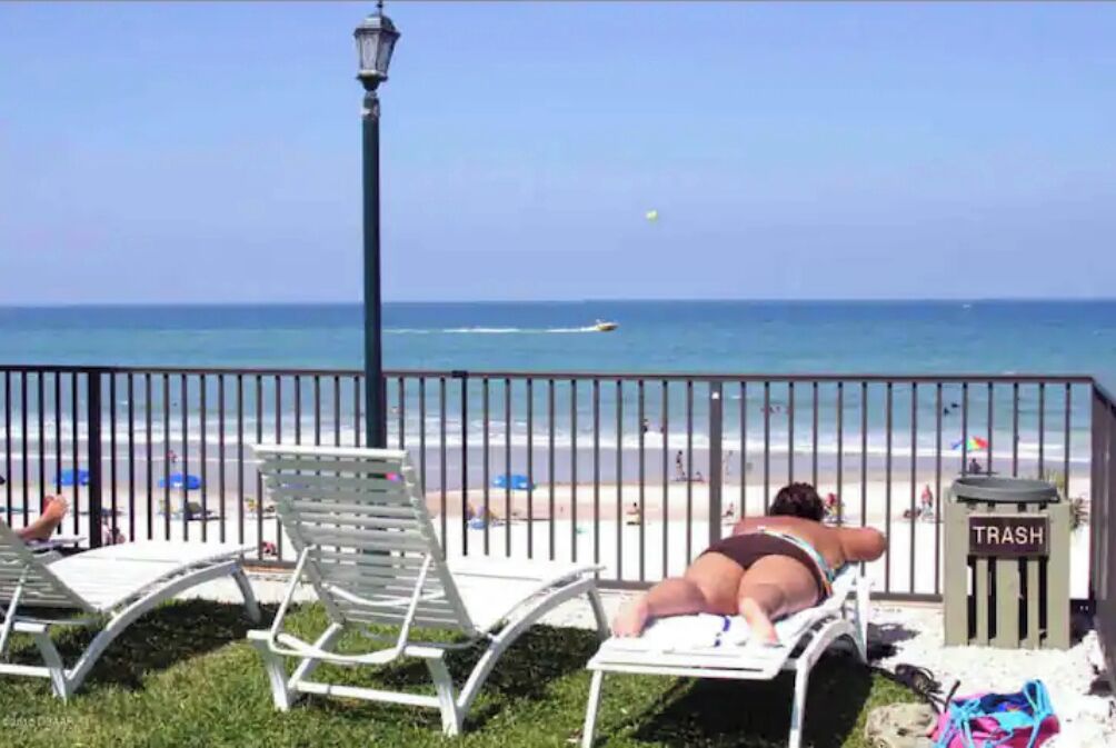 Blick auf einen Strand mit einem Mülleimer mit der Aufschrift 'TRASH' und einer Laterne.