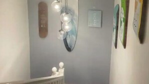 Un interior moderno con una pared gris, una lámpara colgante con varias bombillas y un espejo de forma original.