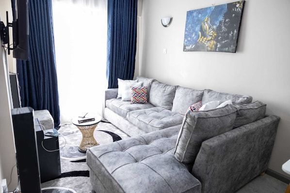 Relax in this stylish living room with a sofa, flat-screen TV, and a small table.