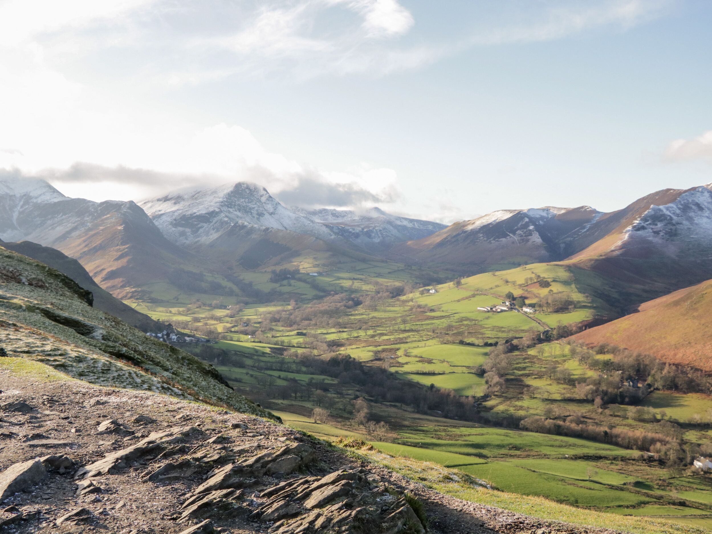 A mountainous landscape with a valley, rocky terrain, and a small settlement.