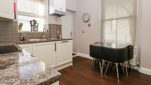 A modern kitchen with white cabinets, granite countertops, a built-in stove, and a dining area with a glass table and chairs.