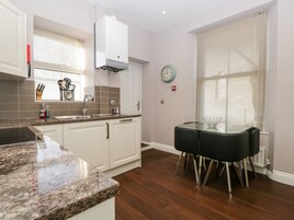 A modern kitchen with white cabinets, granite countertops, a built-in stove, and a dining area with a glass table and chairs.