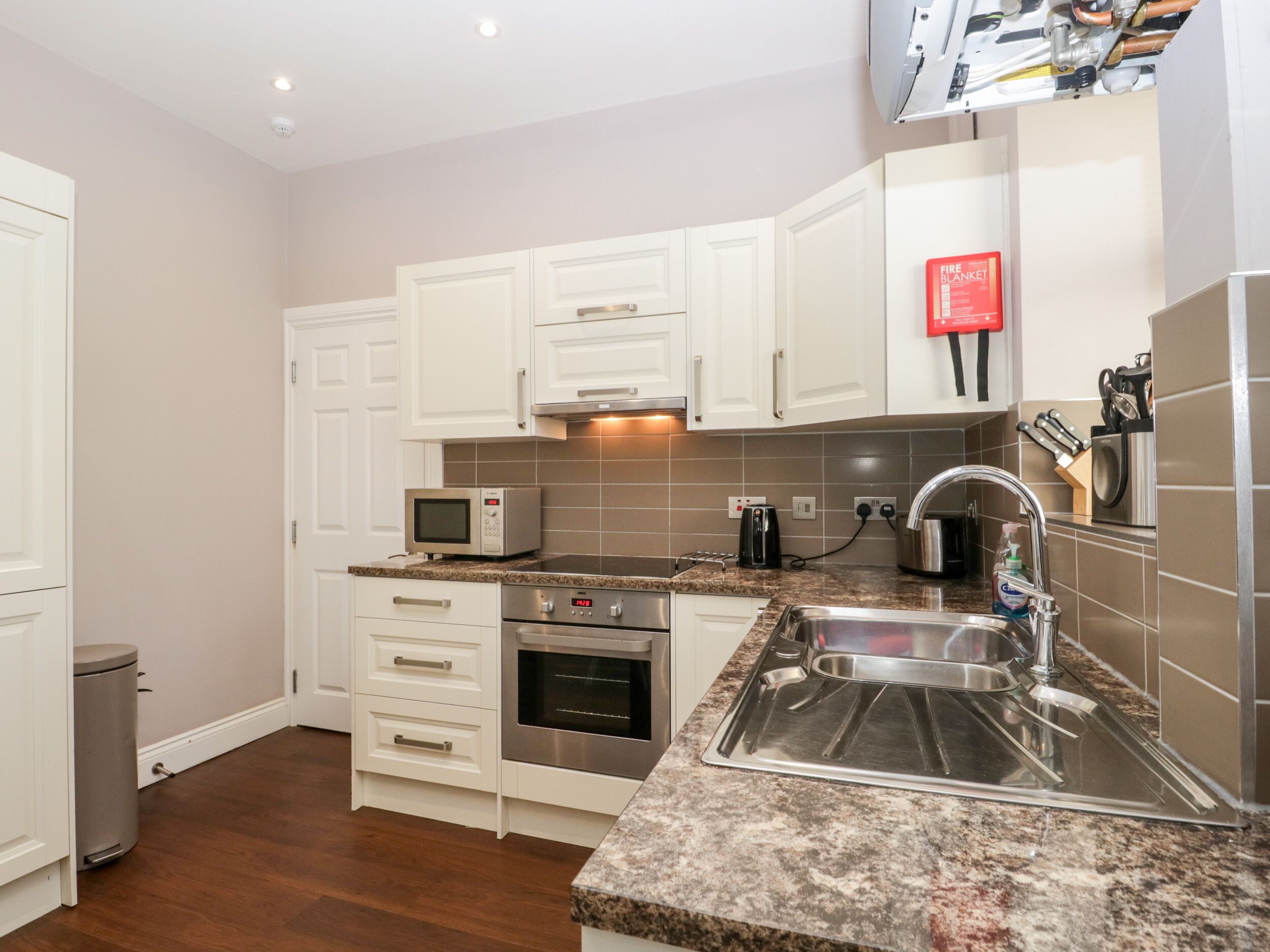 A compact kitchen with white cabinets, a microwave, a toaster, and a sink.