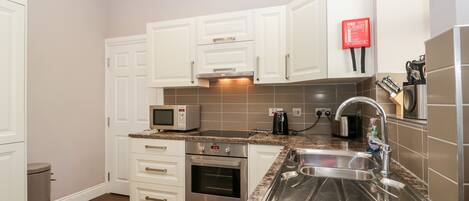 A compact kitchen with white cabinets, a microwave, a toaster, and a sink.