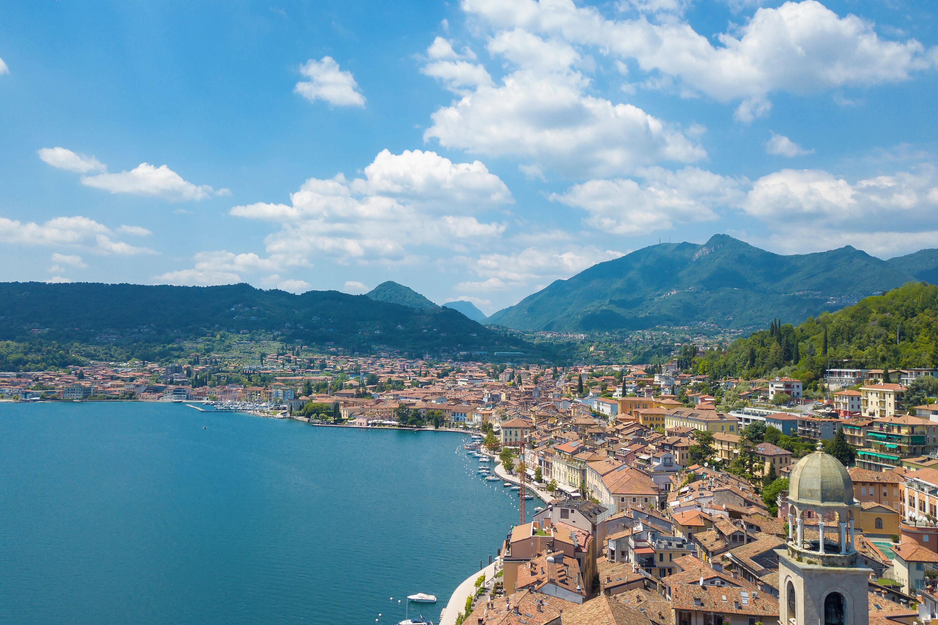 Une ville côtière dotée d’un port de plaisance, de bâtiments historiques et bordée de montagnes.