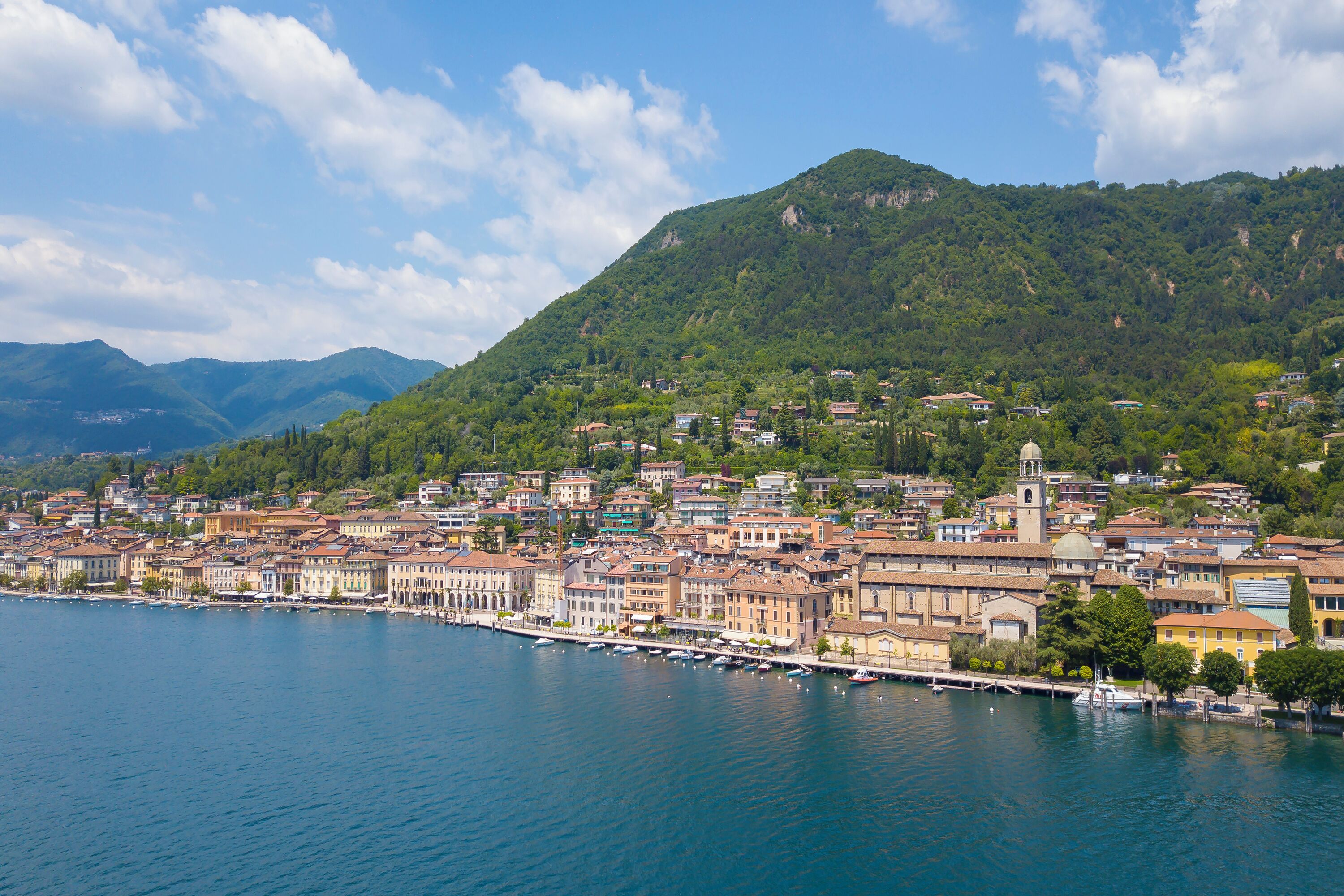 A coastal town with historic buildings along a waterfront, a prominent church, and a mountainous backdrop.