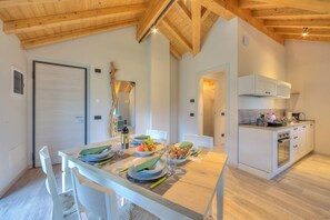 A modern kitchen with white cabinets, a built-in oven, and a dining area with a wooden table set for two.