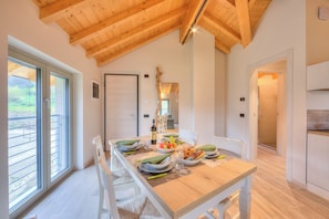 Enjoy meals in this spacious dining area with a long table set for four, featuring a kitchenette with a refrigerator and countertop.