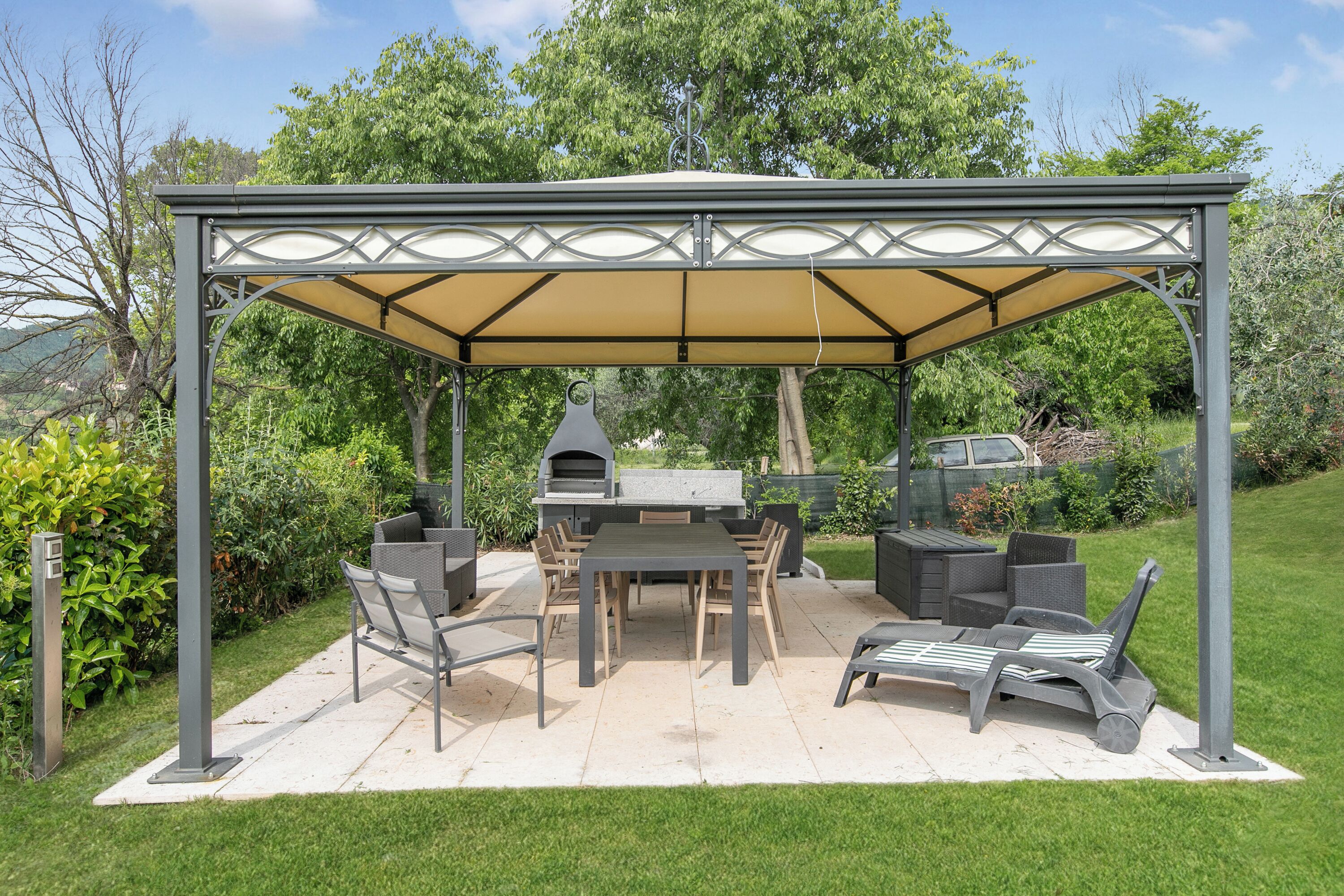 A covered outdoor patio with a grill, dining table, and seating.
