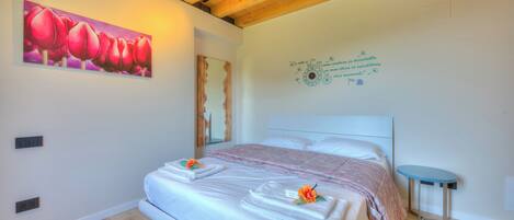 A modern bedroom with a large bed, a small table, and a decorative wall piece.