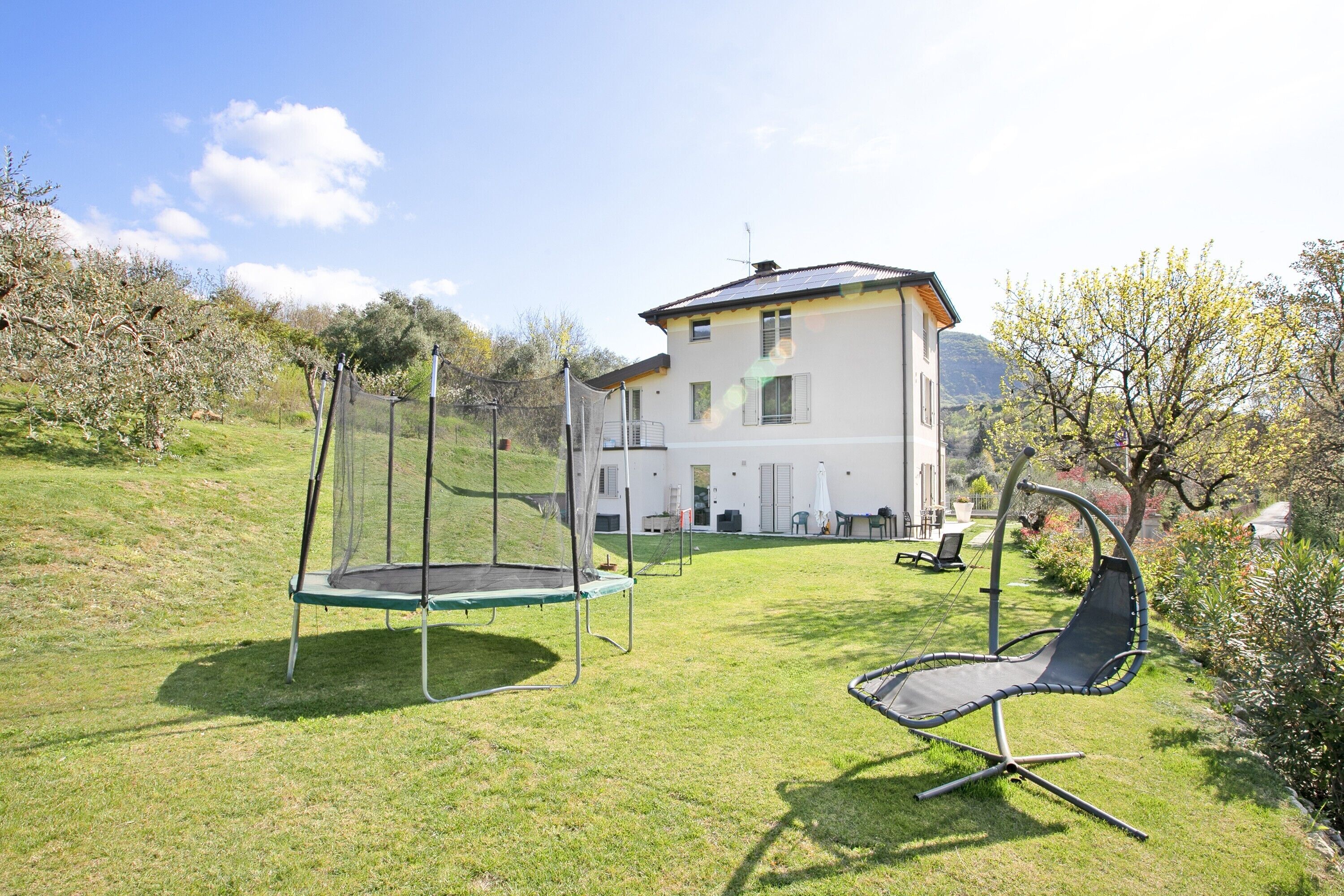 Ein Haus mit Trampolin und einer Schaukel im Garten.