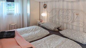 Una habitación de hotel con cama, dos mesitas de noche, una lámpara y un cabecero decorativo.