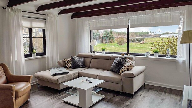 Una sala moderna con un sofá modular, una mesa de centro de vidrio y vistas al exterior.