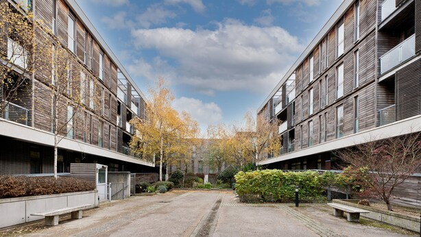 Sisäpiha, jossa on päällystetty kävelyreitti, penkkejä ja syksyisessä loistossaan kukkivia puita.