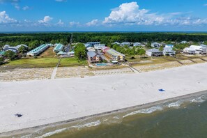 A coastal property with a beach, a swimming pool, and a variety of buildings.