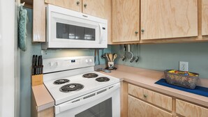 Cocina con estufa blanca, microondas y muebles de madera.