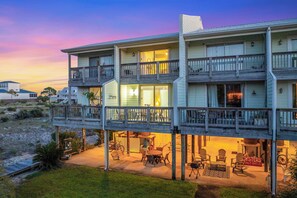 A multi-story beachfront property with a covered outdoor seating area and a visible restaurant sign.