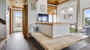 A modern interior with a wooden ceiling, a reception desk, a flat-screen TV, and framed artwork on the walls.