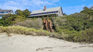 A beachfront property with a large house, a wooden staircase, and dense shrubbery. - Haystack Close North (Cannon Beach)