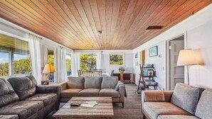 A cozy living room with leather sofas, a wooden coffee table, and a view of the outdoors. - Haystack Close North (Cannon Beach)