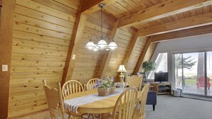 Een houten interieur met een eettafel, stoelen en een kroonluchter.