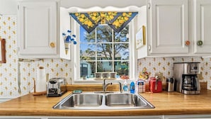 Una cocina con un lavamanos doble, un tostador, una cafetera y una ventana con vistas al exterior.