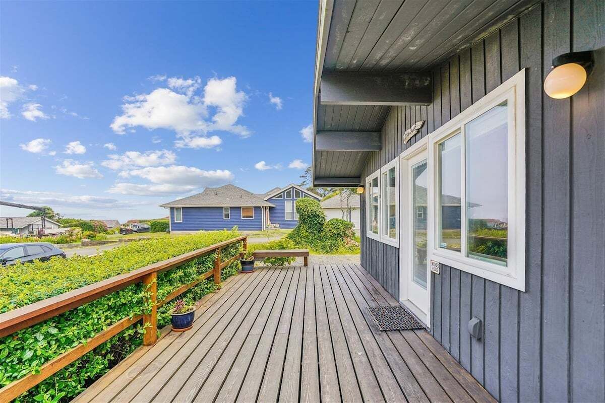 A wooden deck with a railing, a bench, and potted plants.
