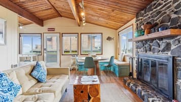 A cozy interior with a stone fireplace, wooden ceiling, and a dining area with a view.