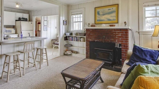 A cozy living room with a fireplace, a kitchen area with a bar, and a dining area with stools. - Sisters - 1 Block to the Beach! (Cannon Beach)