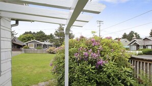 A residential area with a white pergola, a well-maintained lawn, and a house with a visible garage. - Sisters - 1 Block to the Beach! (Cannon Beach)