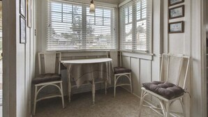 A room with a bay window, a table, two chairs, and a hanging light fixture. - Sisters - 1 Block to the Beach! (Cannon Beach)