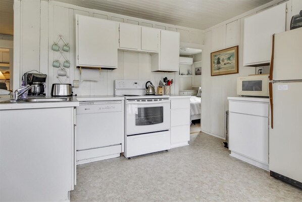 Kitchen features an oven, stovetop, microwave, and sink with faucet.
