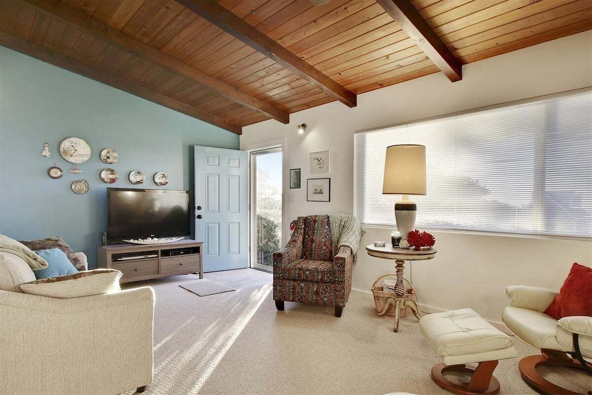 A living room with a TV, patterned armchair, and a lamp near a window.