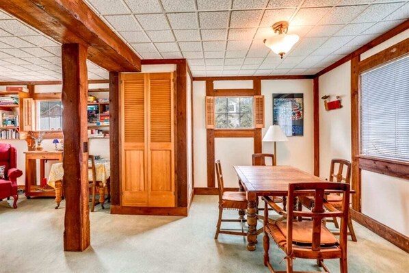 A dining area with a wooden table and chairs, a wooden door, and a window with blinds.
