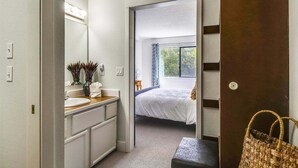 Ein modernes Badezimmer mit Waschtisch, Spiegel und einem großen Fenster.