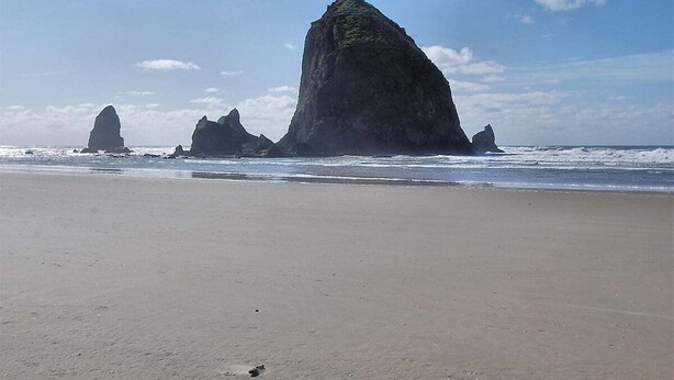 Ein Strand mit großen Felsformationen im Hintergrund.