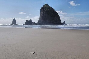 Ein Strand mit großen Felsformationen im Hintergrund.