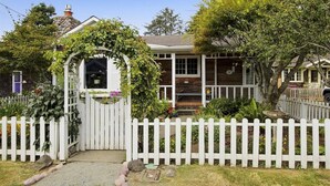 A house with a white picket fence, a covered porch, and a stone chimney.
