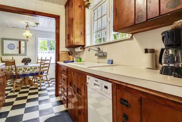 Una cocina con armarios de madera, lavavajillas y cafetera.