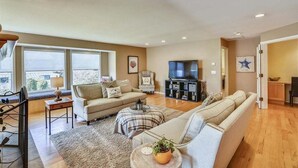 A spacious living room with a sofa, a television, and a dining area.