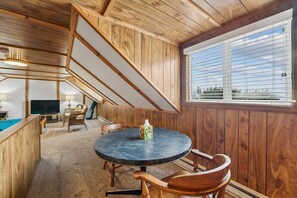 Ein Zimmer mit Holzwänden, einem runden Tisch und einem Fenster mit Jalousien.