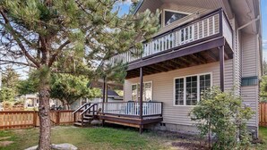 Ein zweistöckiges Haus mit überdachter Veranda und einer kleinen Terrasse.