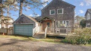 A two-story house with a front porch, a garage, and a small deck. - The Walter House - Quiet Neighborhood! (Cannon Beach)