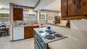 A compact kitchen with a stove, dishwasher, and wooden cabinets. - The Walter House - Quiet Neighborhood! (Cannon Beach)