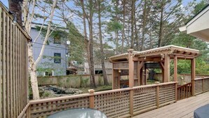A wooden deck with a glass table and a wooden gazebo.