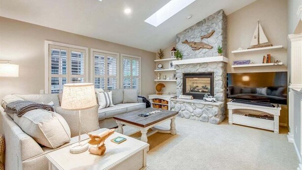 A living room with a stone fireplace, a sofa, a coffee table, and a television.