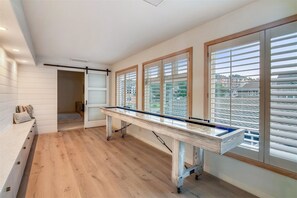Enjoy leisure activities in this spacious room featuring a large pool table and large windows with horizontal blinds.