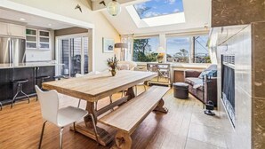 Una cocina amplia con una mesa de madera y bancos, un ventanal con vistas y un tragaluz.